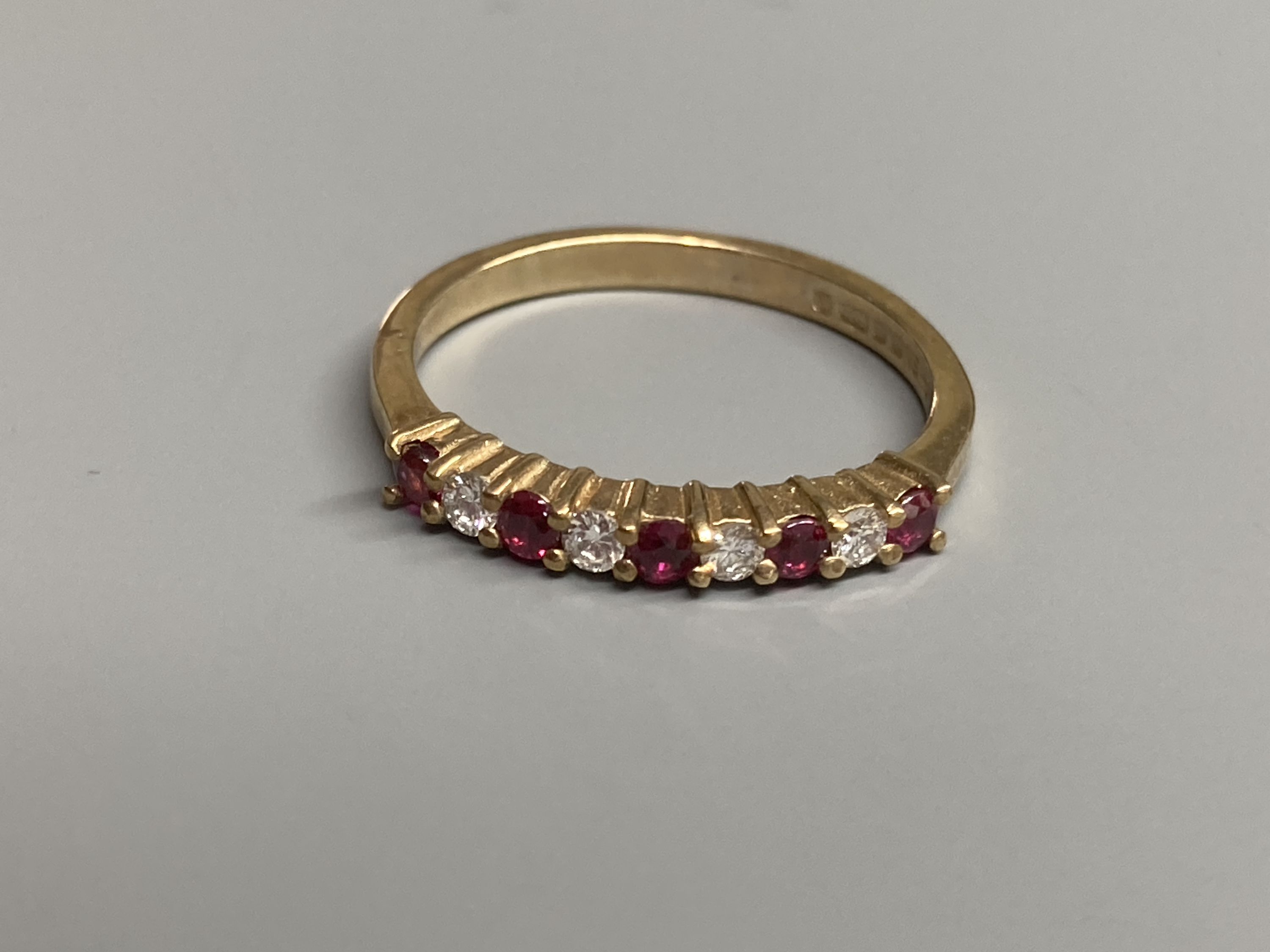 A modern 9ct gold, ruby and diamond set half hoop ring and a similar amethyst ring and two other 9ct gold gem set rings